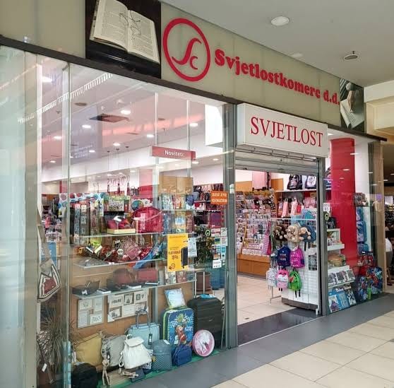 Ulaz u knjižaru Svjetlost u tržnom centru Zenica City Center, natpis Svjetlostkomerc d.d. iznad izloga sa školskim priborom i torbama